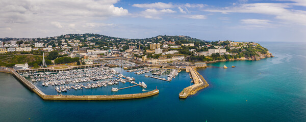 Fototapeta premium Aerial view of Torquay Marina on a sunny day, featuring yachts, boats, promenade, and blue sea along the English Riviera coastline