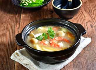 Seafood and tofu casserole topping with coriander served in broth side view of Asian food