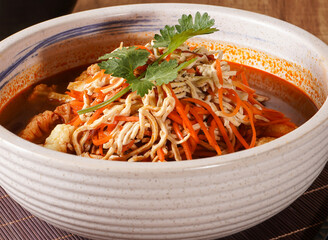 Spicy and savory stir fry with shredded vegetables, cauliflower, and chili sauce in broth close up side view of Asian food
