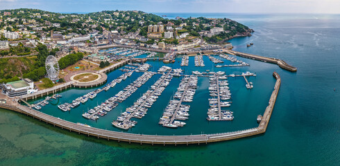 Aerial view of Torquay Marina on a sunny day, featuring yachts, boats, promenade, and blue sea...