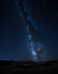 A mesmerizing night view of the deserts vast expanse, where sand dunes stretch beneath a starstudded sky, creating a breathtaking contrast between earth and cosmos