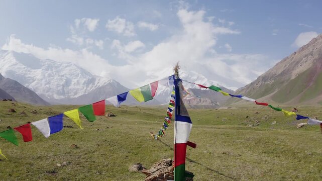 Lifting UP camera movement over holy Puja stupa with prayer flags at 3600m Base Camp with vast panoramic view of Pamir mountains with Lenin Peak wall. Lenin peak expedition in Kyrgyzstan, Central Asia
