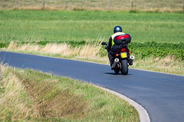 Obraz premium Motorcyclist drving a bending road at the Flemish countryside in Zonnebeke, West Flanders, Belgium