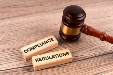 Top view of gavel and wood block with text compliance and regulations