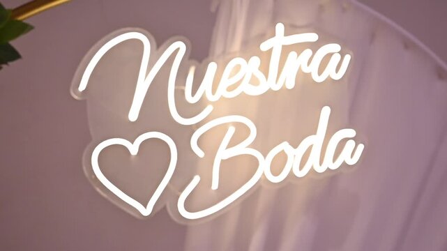 Neon sign saying nuestra boda lights up wedding venue