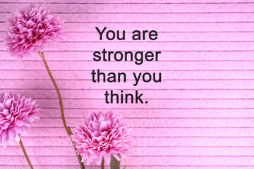 Flower on pink background with inspirational quotes you are stronger than you think