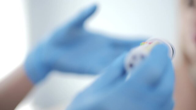 Gloved hand holding medical syringe-like device