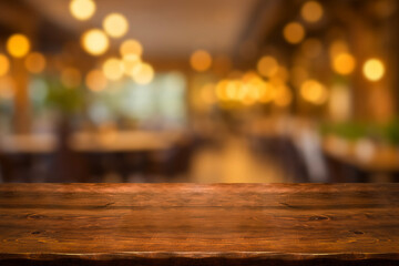 Empty wooden table  bokeh light background. Tables and chairs in the lobby of restaurant. Visitors to restaurant for dinner. Cozy bokeh lightening. Beautiful bright interior. Blurred bokeh basic