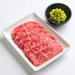 Marbled wagyu slices with wasabi accent on plate, culinary presentation on white background