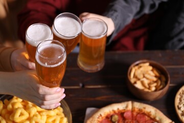 Friends with beer and snacks at wooden table, closeup