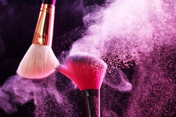 Makeup brushes with colorful eye shadows in neon lights on black background, closeup