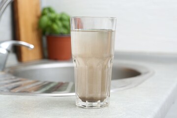 Glass with dirty water near sink indoors