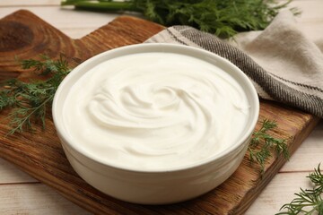 Tasty sour cream and dill on white wooden table, closeup