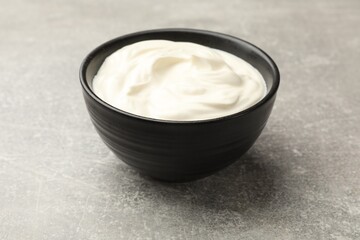 Tasty sour cream in bowl on grey table, closeup