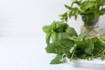 Different fresh green herbs on white tiled table, closeup. Space for text