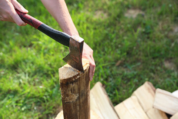 Man chopping firewood with axe outdoors, closeup. Space for text