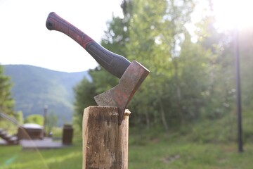 Metal axe on wooden log outdoors, closeup. Space for text