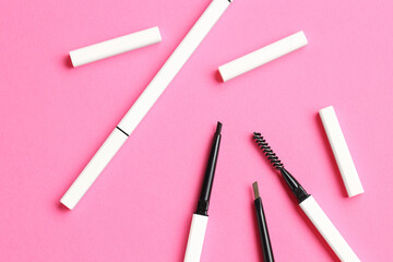 Twist up eyebrow pencils on bright pink background, flat lay