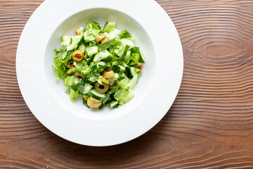 Mediterranean salad with green olives on white plate in close-up