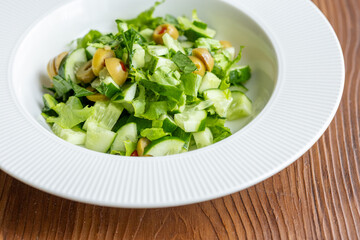 Mediterranean salad with green olives on white plate in close-up