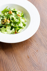 Mediterranean salad with green olives on white plate in close-up