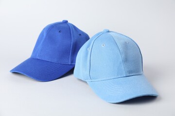 Blue baseball caps on grey background, closeup. Mockup for design