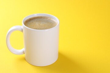 Aromatic coffee in cup on yellow background, closeup. Space for text