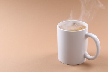 Aromatic coffee in cup on beige background, closeup. Space for text