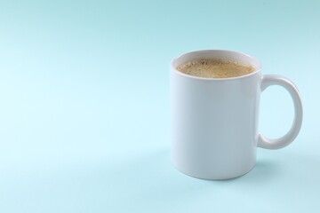 Aromatic coffee in cup on light turquoise background. Space for text
