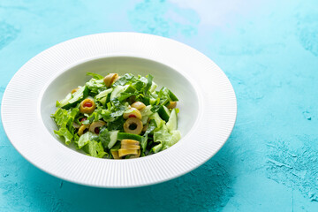 Mediterranean salad with green olives on white plate in close-up