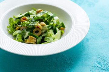 Mediterranean salad with green olives on white plate in close-up