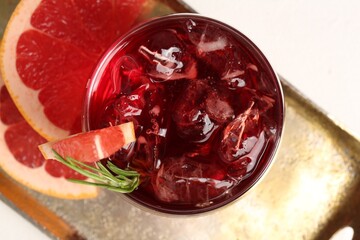 Tasty cocktail with grapefruit, ice cubes and rosemary on white table, top view