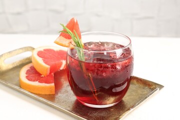 Tasty cocktail with grapefruit, ice cubes and rosemary on white table, closeup