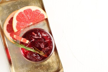 Tasty cocktail with grapefruit, ice cubes and rosemary on white table, top view. Space for text