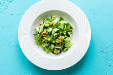 Mediterranean salad with green olives on white plate in close-up