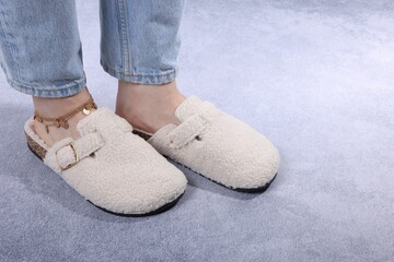 Woman in stylish white slippers on grey textured floor, closeup