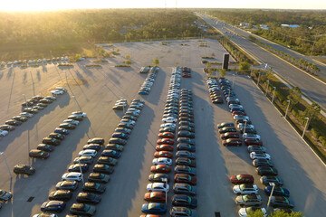 Aerial view of dealership parking lot with many brand new cars for sale. Development of american...