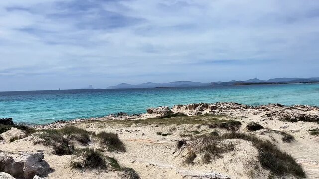 White sand beach on a narrow strip of land on Formentera. Blue famous beach with people relaxing on vacation in the mediterranean sea with luxury vessels and boats. Turquoise sea.
