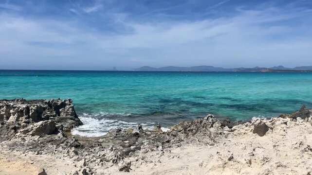 White sand beach on a narrow strip of land on Formentera. Blue famous beach with people relaxing on vacation in the mediterranean sea with luxury vessels and boats. Turquoise sea.