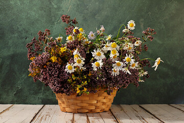 Flower arrangement of wild medicinal herbs on a wooden table in a basket, a bouquet of St. John's...