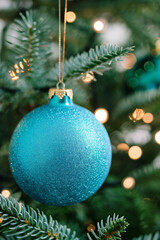 Blue Christmas ornament hanging on fir tree. Holiday decoration concept.