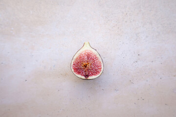 Higo morado partido por la mitad visto desde arriba. Imagen minimalista, textura orgánica, fondo neutro. Fotografía cenital de fruta natural y saludable.