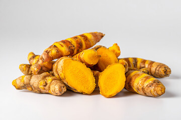 Fresh turmeric roots, whole and sliced, for culinary and health uses.