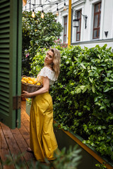 beautiful girl with basket of lemons in cafe on summer day
