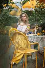 beautiful girl with glass of lemon colored lemonade in hand in cafe on summer day
