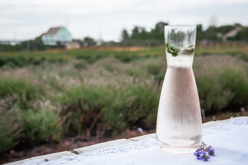 Sweaty jug of cool drink and mint leaves sits on a table covered with a tablecloth against the...