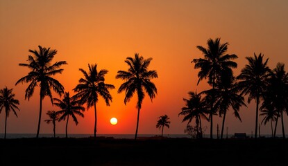 Obraz premium Stunning tropical sunset silhouettes palm trees against a vibrant orange sky over the ocean