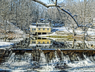 A view of a snowy house in winter reflecting on the water 
