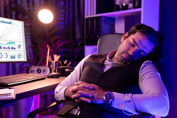Smart businessman leaning on chair with working desk, unfinished product service sales channel report, waiting for market data long time updated at purple neon dark light room at late night. Surmise.