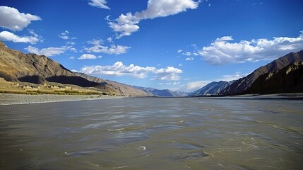 Scenic view of the Indus River, a historic waterway flowing through Pakistan and India, featuring calm waters, fertile riverbanks, traditional boats, rural villages, and lush vegetation
